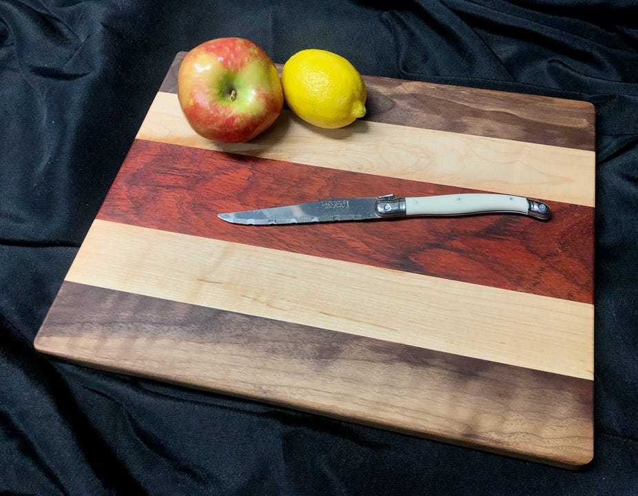 Made from Padauk, Walnut & Hard Maple this cutting board has a five layer striped design. This board measures: 13”x11”x.6”